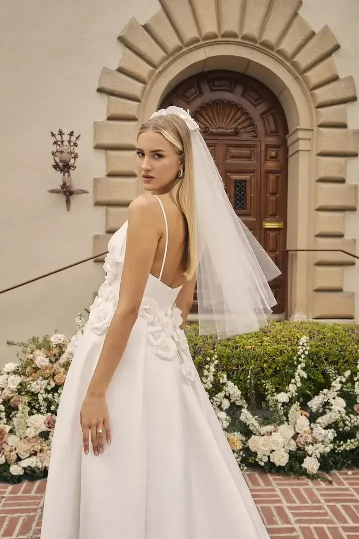 model is wearing a bridal gown with a short veil